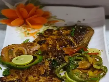 Close-up of grilled fish garnished with vegetables at Bloft Hotel Vellore restaurant.