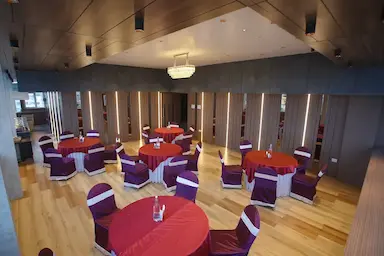 Banquet hall at Bloft Hotel Vellore set up for a formal event with purple chair sashes.