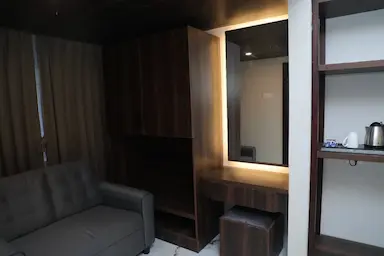 Modern hotel room interior at Bloft Hotel, Vellore featuring dressing area, sofa seating, and in-room tea kettle.