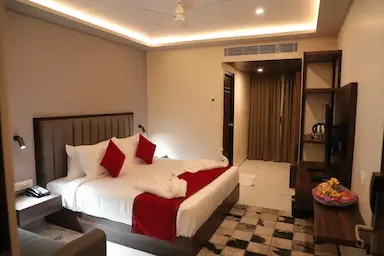 Luxury hotel room at Bloft Hotel, Vellore featuring king-size bed, LED lighting, modern amenities, and welcome fruit basket.