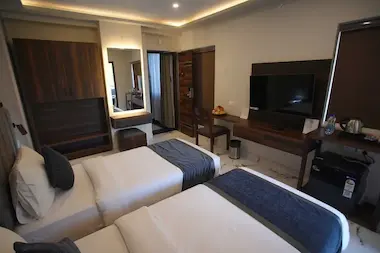 Modern Studio Room setup at BLOFT HOTEL, Vellore with twin beds, minibar, flat-screen TV, and ambient lighting